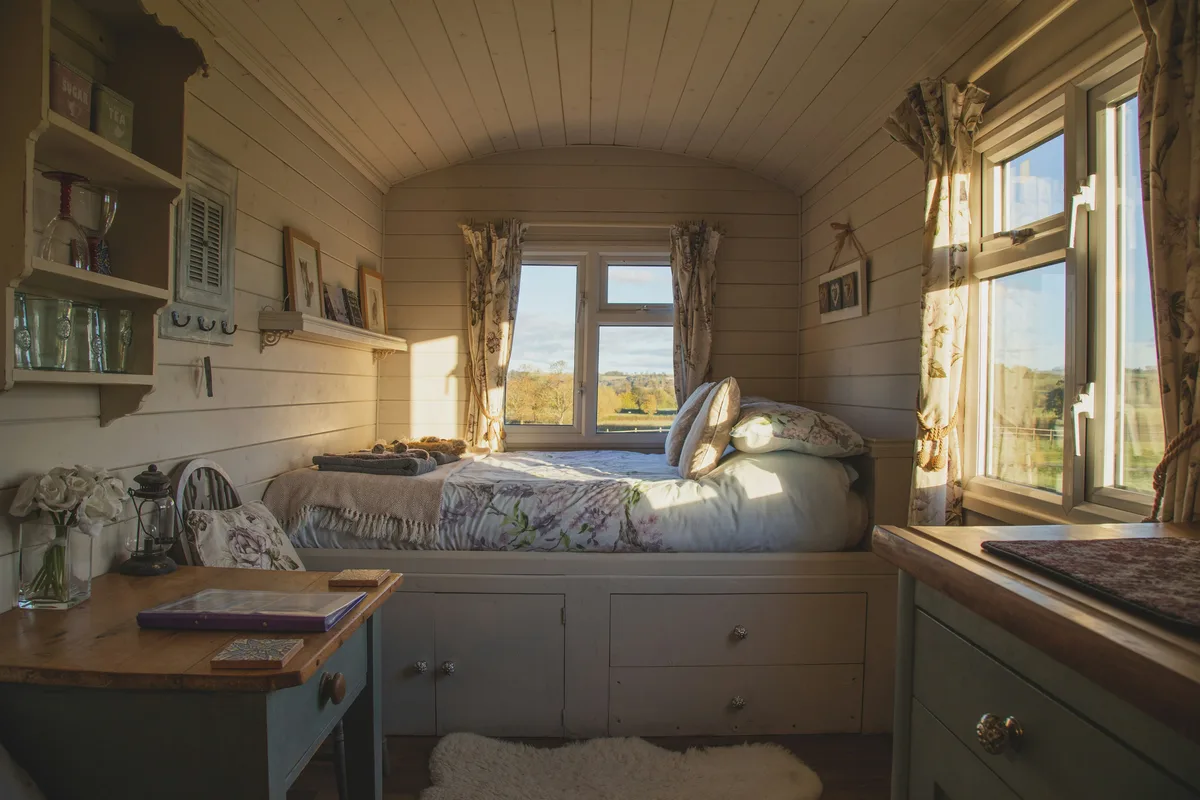 Tiny bedroom with storage bed featuring drawers underneath and small wooden desk