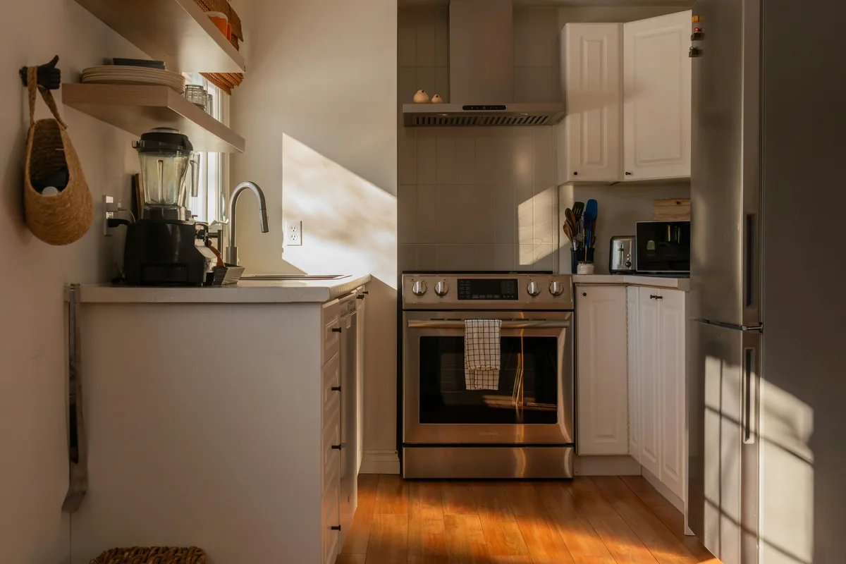 Sunlit compact kitchen with open shelves holding dishes and blender
