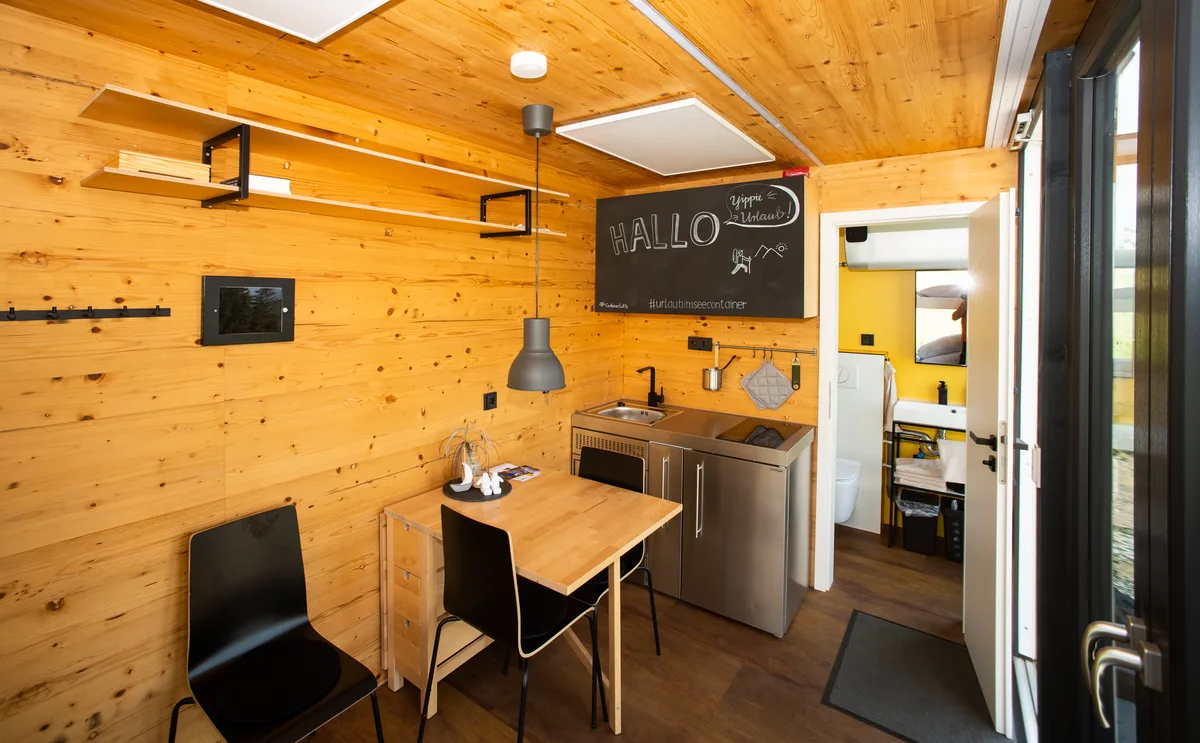 Container tiny house interior with wood walls dining table and kitchenette