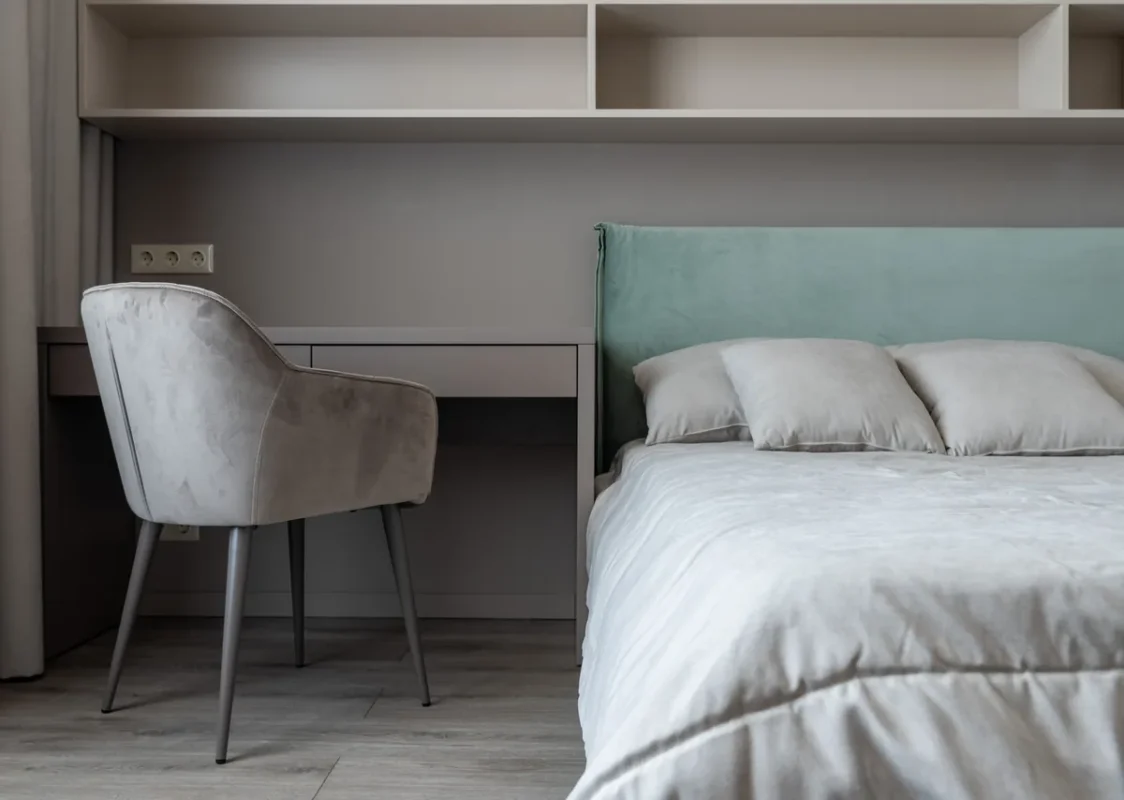 Compact apartment corner with bed next to a small table and chair