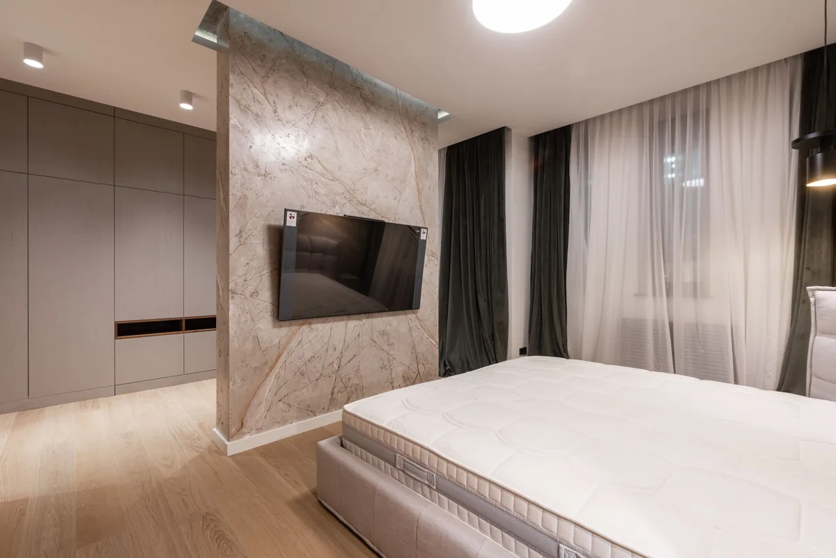 Small apartment bedroom with bed placed near a wall-mounted TV