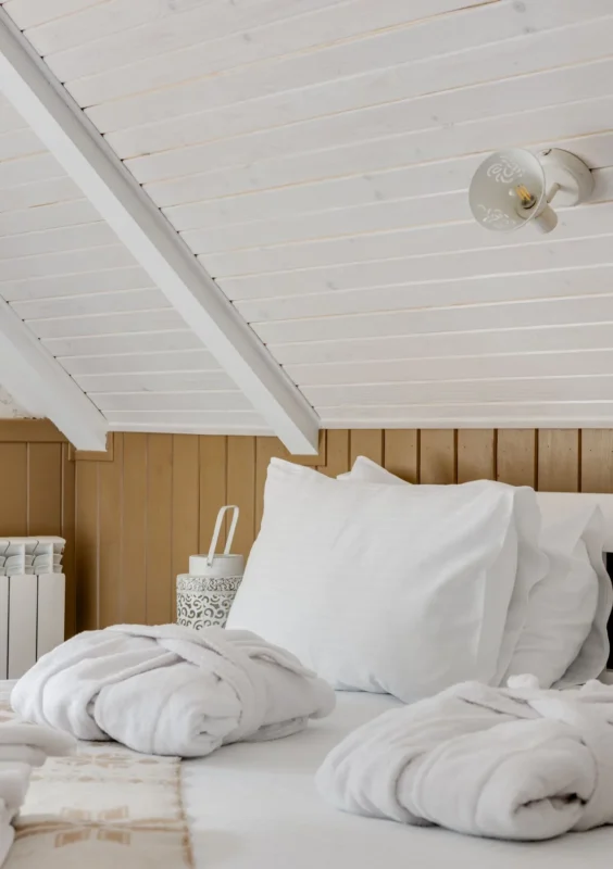 Attic bedroom with white bedding under a sloped ceiling
