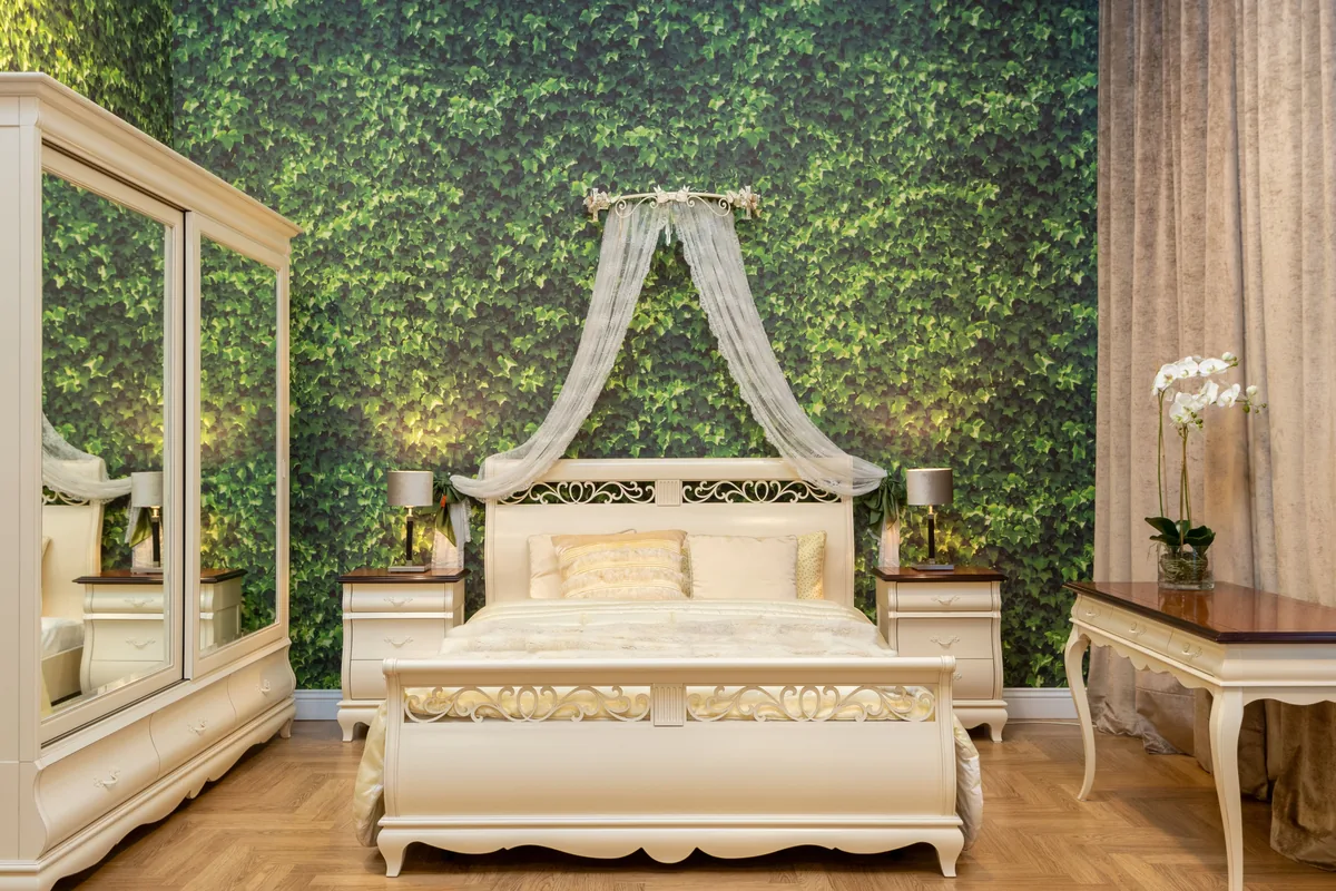 White wooden bed frame against a green accent wall in a small bedroom