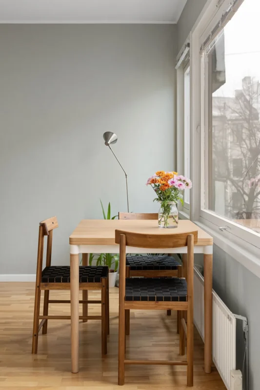 Wooden dining table with chairs by a bright apartment window