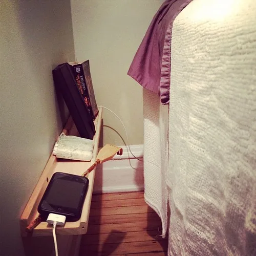 Narrow bedside shelf beside a bed