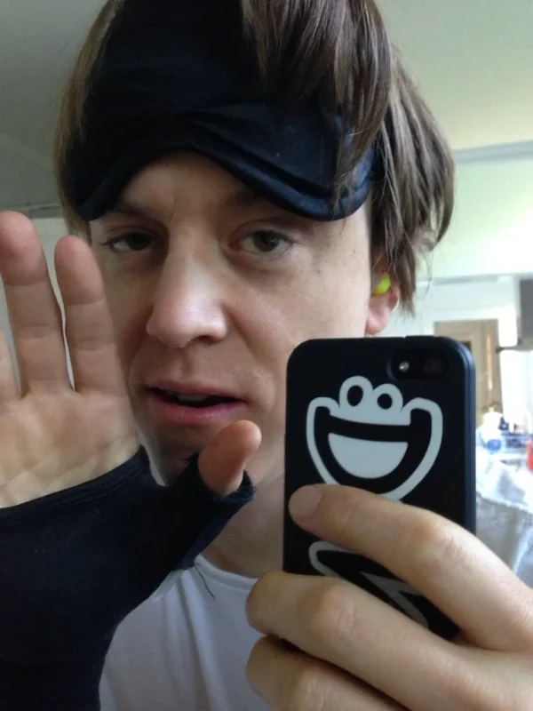 Person wearing a sleep mask with earplugs nearby
