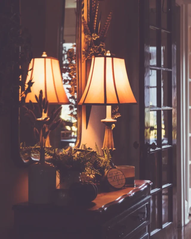 Two lit table lamps on a wooden dresser