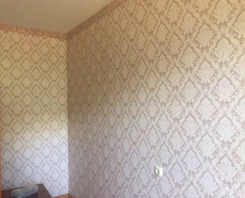 Patterned wallpaper accent wall in a small apartment living area, a rental-friendly decor idea