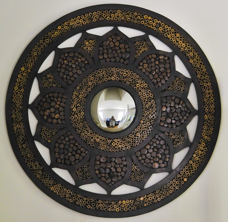 Round mirror hanging on an apartment wall to reflect light and make a small room feel bigger