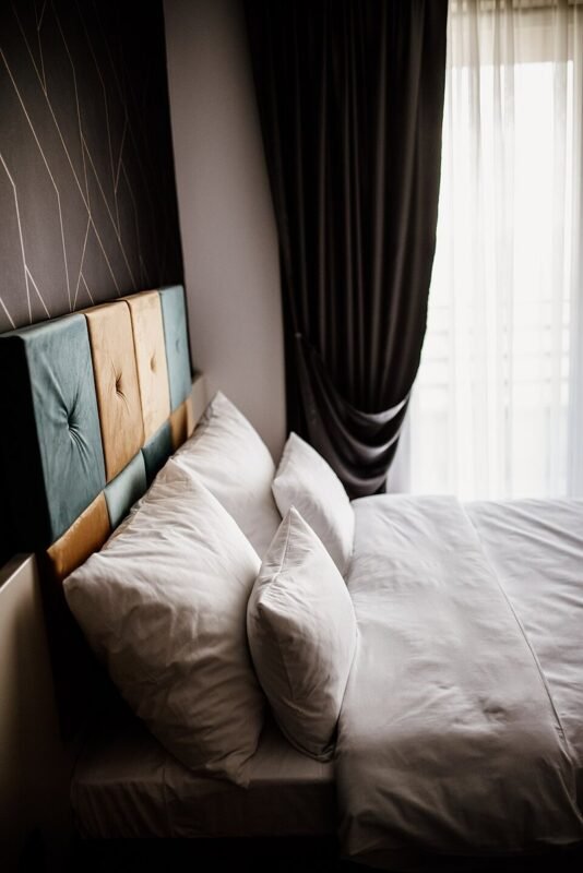 Cozy small bedroom with layered pillows and sheer curtains, styled on a budget
