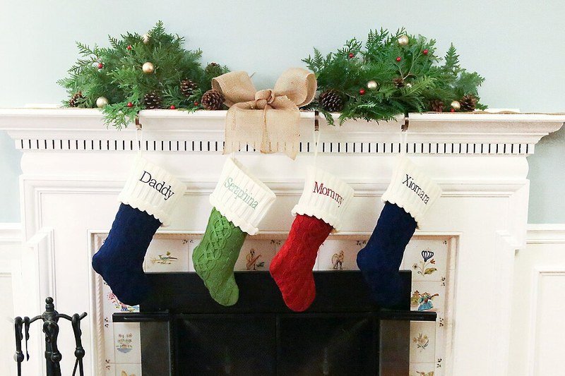 Christmas mantel garland with stockings hanging on a white fireplace