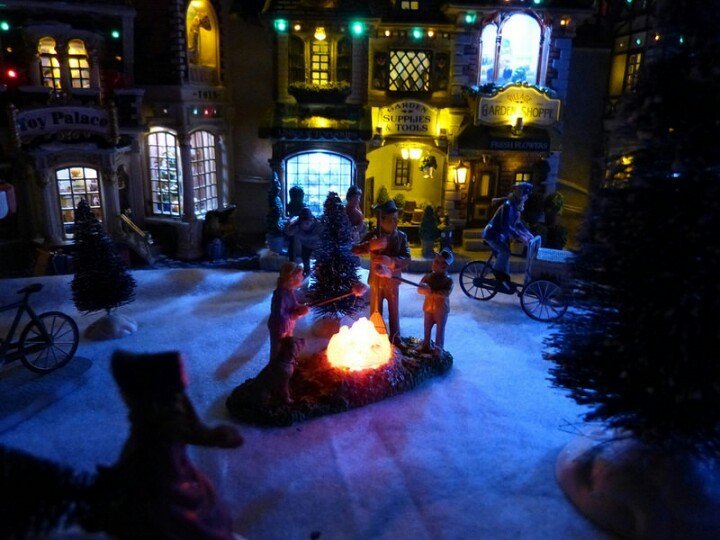 Miniature Lemax Christmas village with tiny glowing houses on a shelf