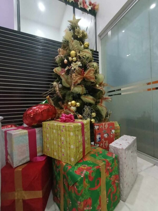 Small Christmas tree with wrapped gifts underneath in a room corner