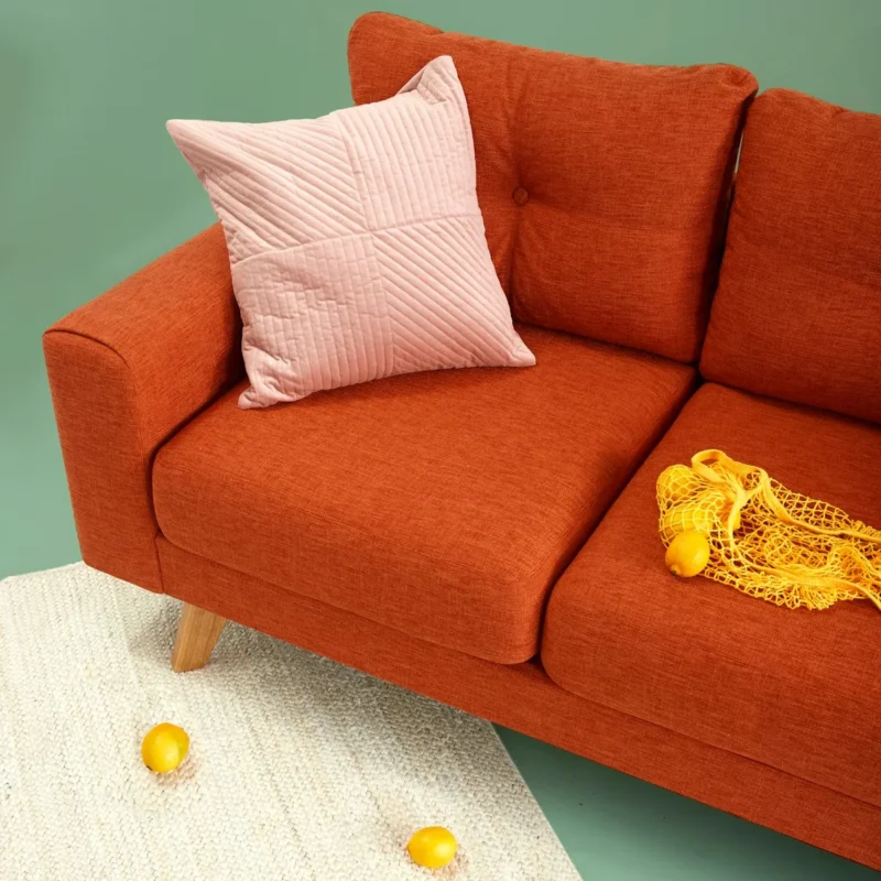 Living room with bold green accent wall behind an orange velvet sofa