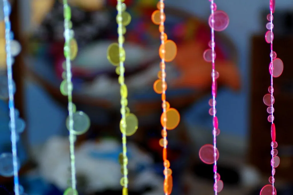 Colorful beaded curtain hanging in a doorway dividing two small rooms