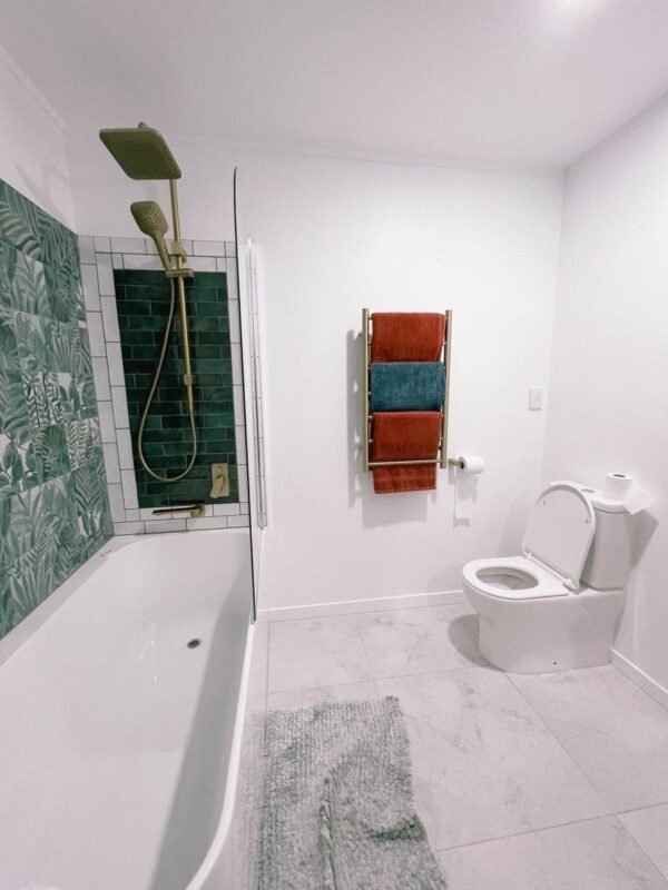 Bright small bathroom with white walls, green subway tile shower and glass panel