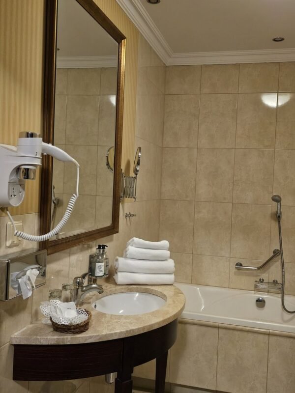 Large framed mirror above a curved vanity in a small hotel bathroom