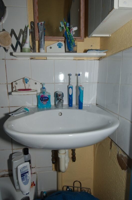 Wall-hung sink with a shelf above for storage in a small bathroom
