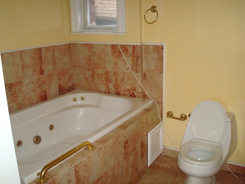 Compact corner bathtub with toilet in a small bathroom