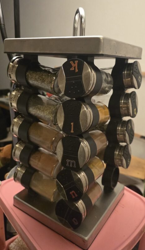 Wall-mounted spice rack with labeled jars freeing up tiny kitchen counter space