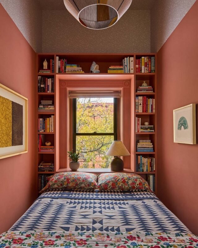 Small terracotta bedroom nook with built-in bookshelves around a sunny window