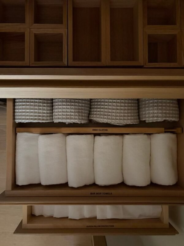 Organized drawer with neatly folded linens and wooden dividers
