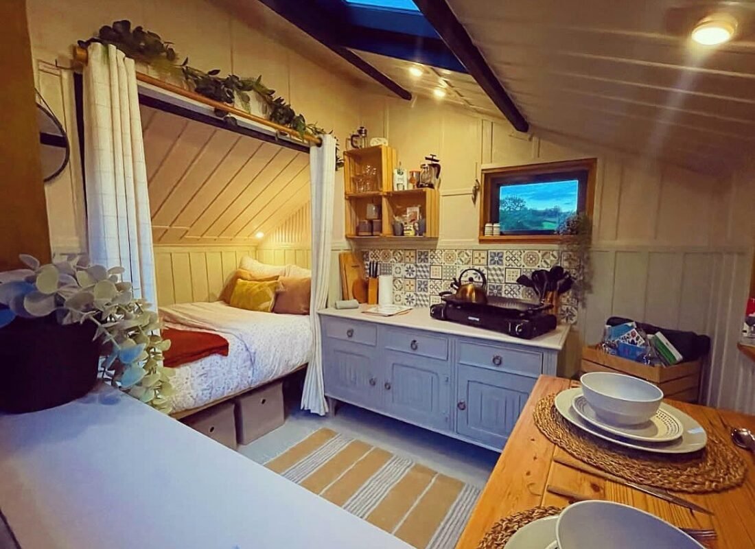 Cozy tiny cabin interior with compact kitchen and bed nook, warm small space living