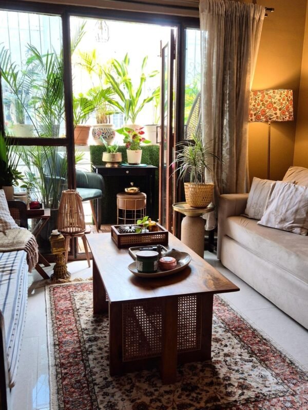 Plant-filled living room with glass doors opening to a lush green balcony, indoor plants for wellbeing