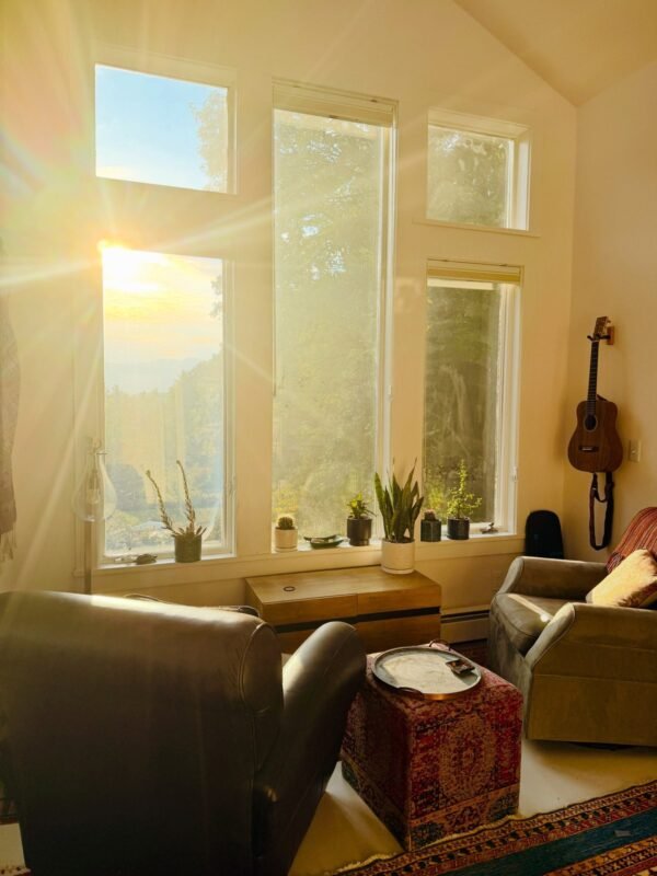 Sunlit living room with tall windows, houseplants and guitar, peaceful slow morning corner