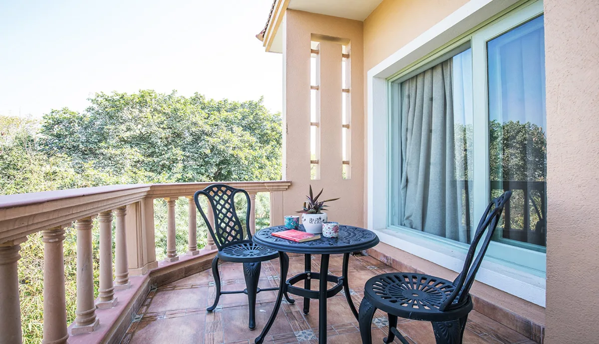 Sunlit balcony table and chairs with a potted plant