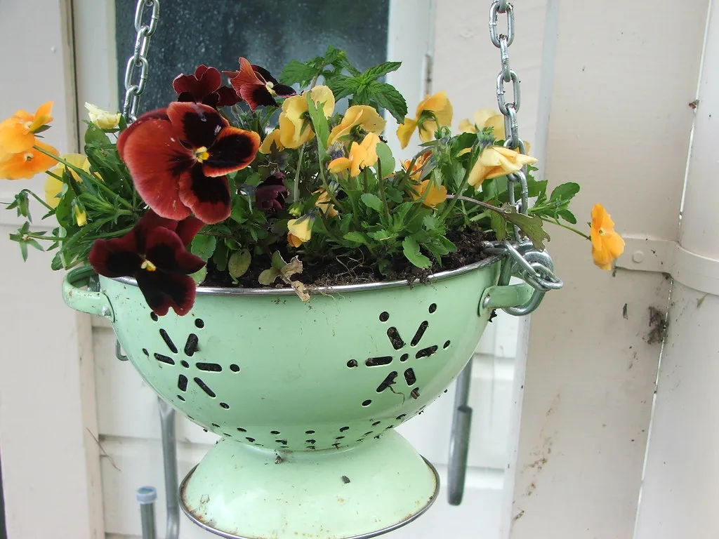 Hanging basket planter made from a colander with pansies