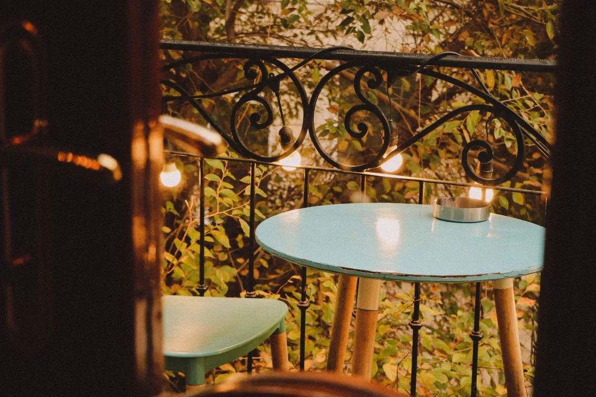 Blue bistro table and chair with string lights on a balcony railing at dusk