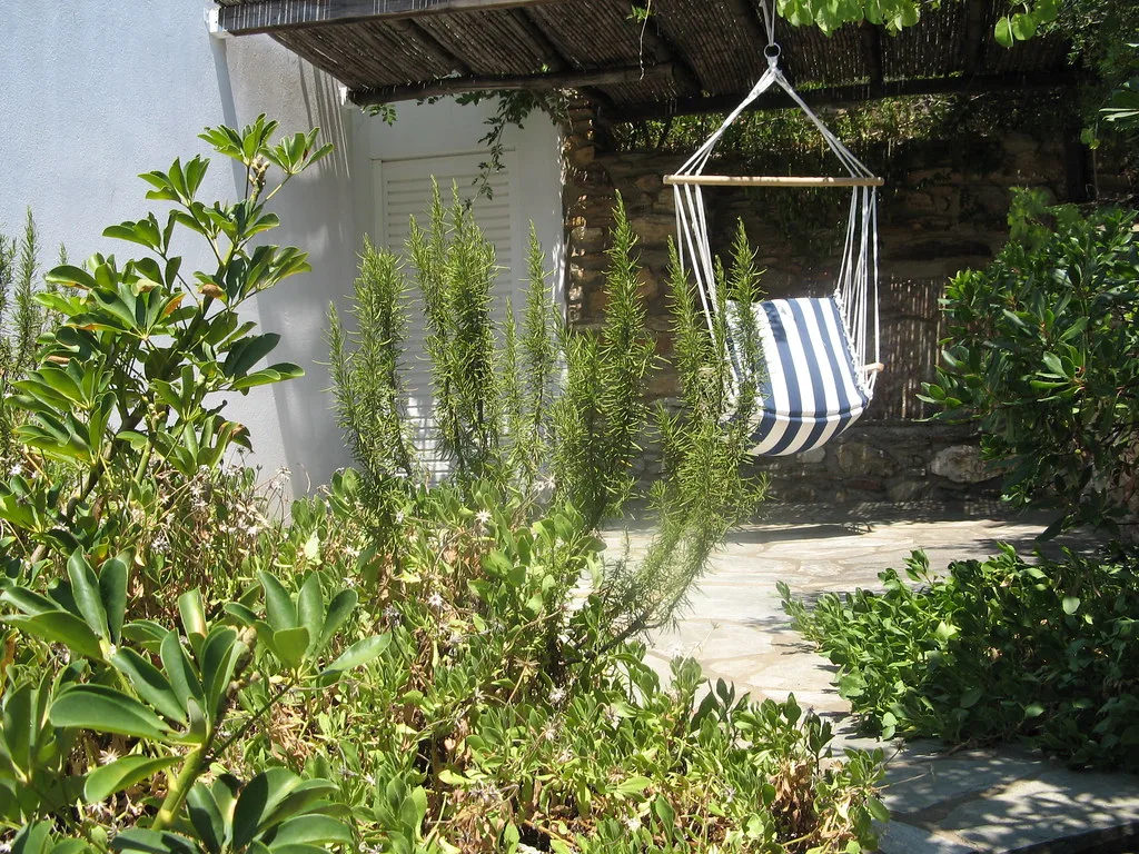 Striped hammock chair under a pergola in a garden corner