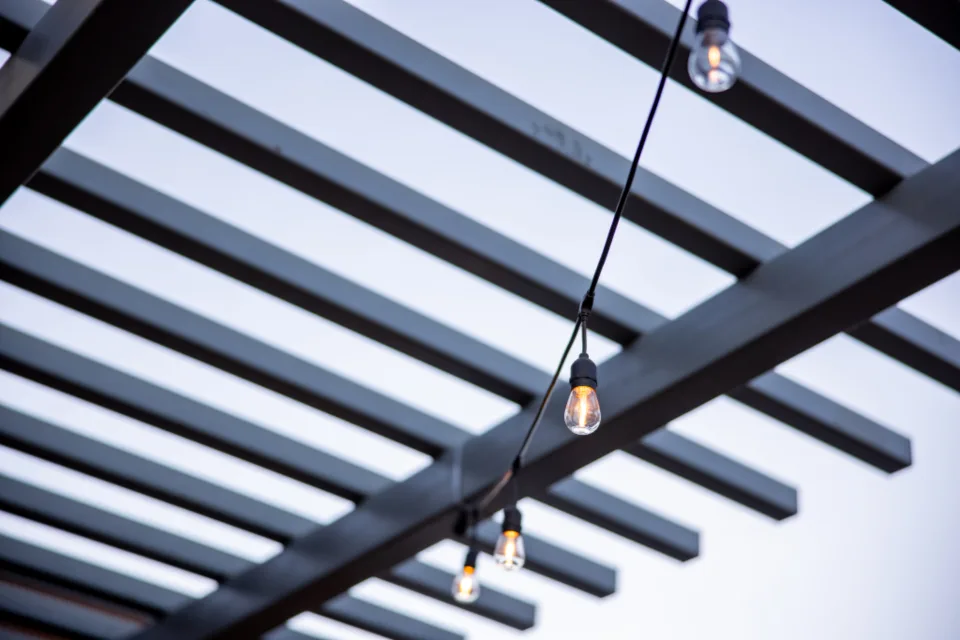 Glowing string lights under a pergola at dusk