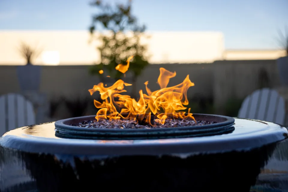 Fire-pit bowl with flames on a patio at dusk