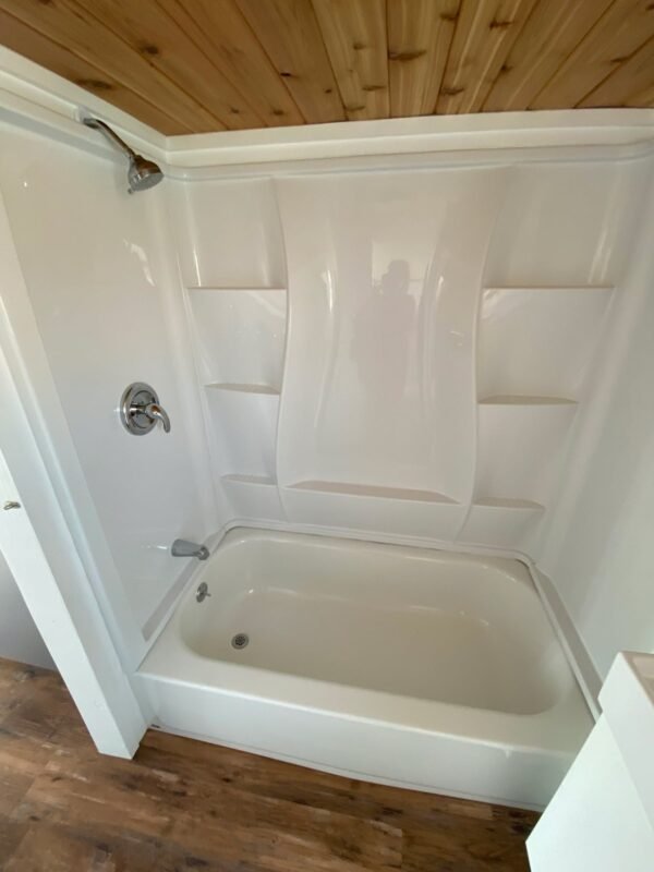 Small white tiny house bathroom with tub and shower combo