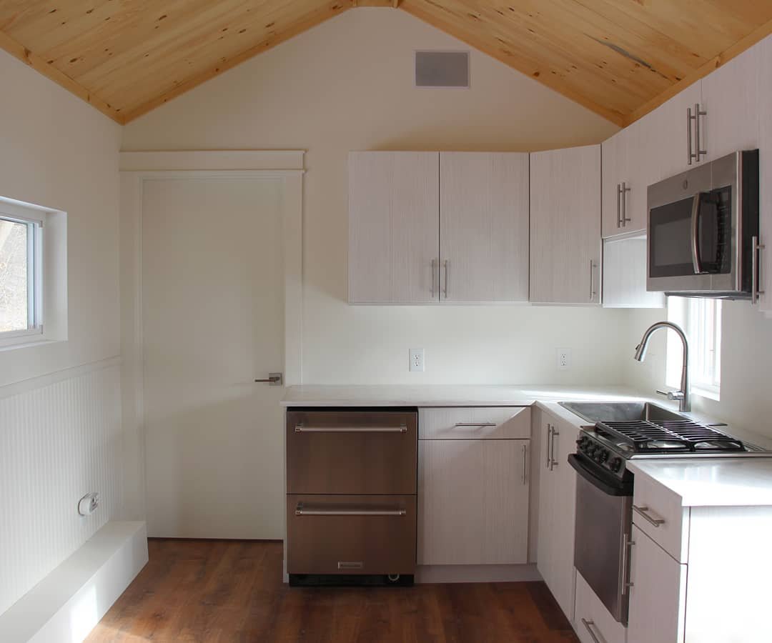 Bright white tiny house kitchen with stainless steel appliances