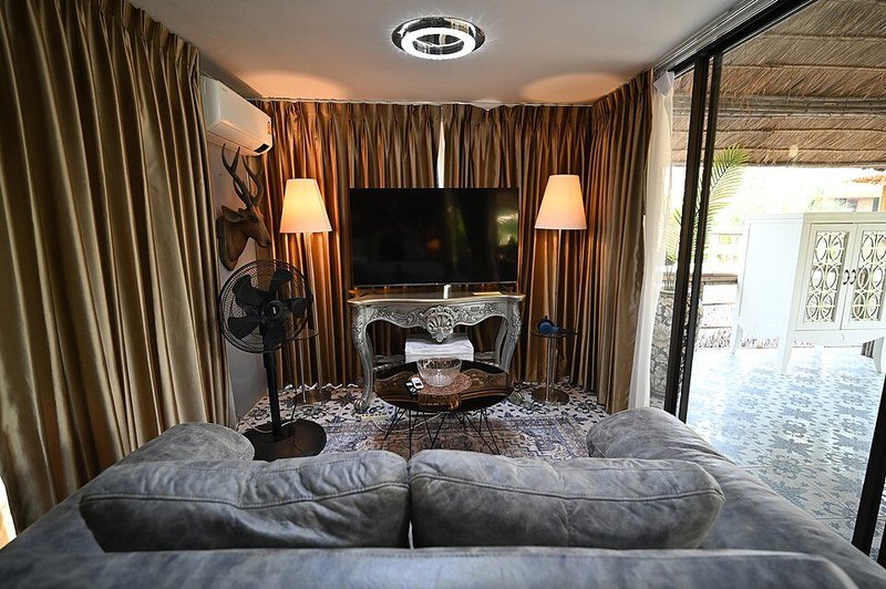 Small living room with gray sofa facing TV on slim console between two floor lamps