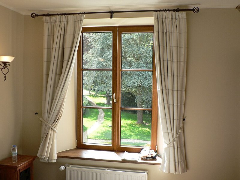 Window dressed with full-length curtains hung wide to clear the glass